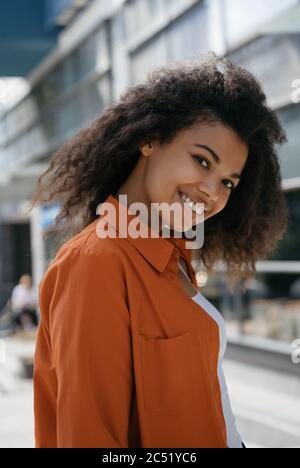 Portrait of young cheerful African American woman posing for pictures, standing outdoors Stock Photo