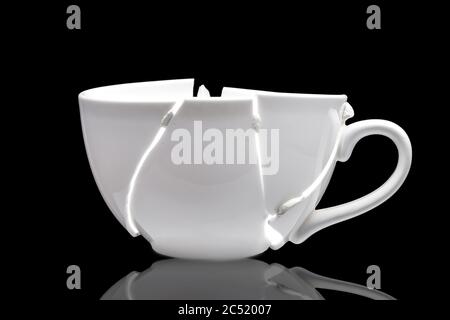 white ceramic cup broken into fragments as a result of the fall and glued together chewing gum in the hope of solving the problem, a concept on the th Stock Photo