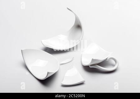 shattered white ceramic tea cup on a white background, concept on the theme of broken and ruined affairs. Stock Photo