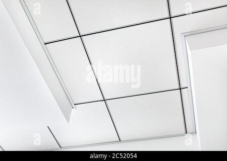 multi level ceiling pattern with three dimensional protrusions and a suspended tiled ceiling white color, close up geometric clear details, nobody. Stock Photo