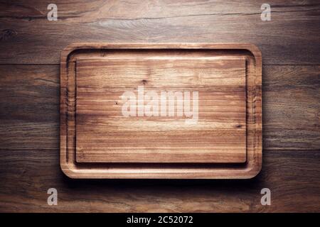 Empty vintage wooden cutting board on wooden table. Overhead view with copy space. Stock Photo