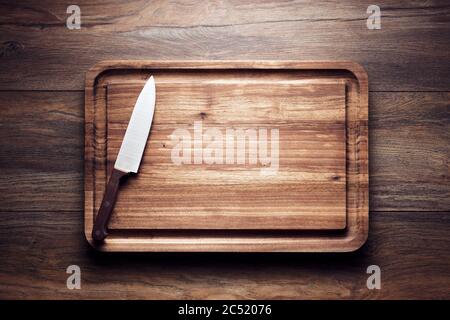 Empty vintage wooden cutting board with knife on wooden table. Overhead view with copy space. Stock Photo