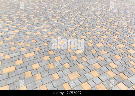 paving stone tiles of square and rectangular shape of gray and yellow are paved in perspective, closeup of the road surface. Stock Photo