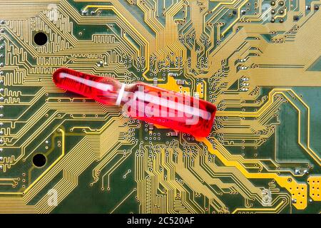 glass ampoule with a red vaccine on a circuit board of a microcircuit with contact tracks concept on theme of vaccination of chipping and chipization Stock Photo