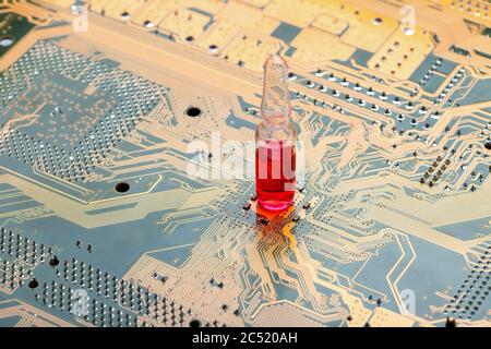 glass ampoule with a red vaccine stand on circuit board of microcircuit with contact tracks concept on theme of vaccination of chipization surveillanc Stock Photo