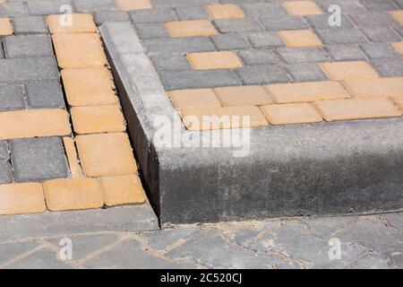barrier border and ramp for the descent of wheeled vehicles from the pedestrian sidewalk onto the road paved with stone tiles  closeup architecture de Stock Photo