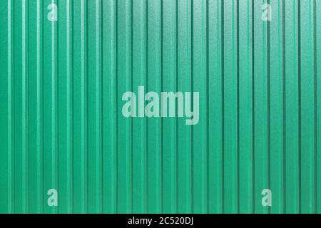 galvanized iron fence with corrugated vertical stripes closeup of the texture of the top coat of a green sheet top view, nobody. Stock Photo