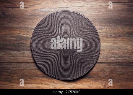Brown wicker food service mat on wooden table. Overhead view. Stock Photo