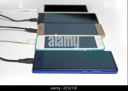 Charging smartphones with usb cables, blurred, isolated on white background Stock Photo