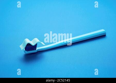Toothbrush and chewing gum representing toothpaste on blue background with copy space. Brushing teeth with refreshing toothpaste concept. Stock Photo
