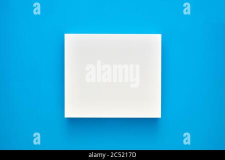 White blank square shape or frame on blue background. Mockup for product or text display. Stock Photo