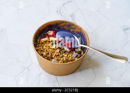 Blue Matcha Bowl with Granola, Blueberries and Banana / Healthy Blue Spirulina Smoothie in Brown Paper Kraft Carton Box. Organic Healthy Superfood. Stock Photo