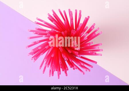 Bunch of pink plastic straws on multi colored pink and purple background. Stock Photo