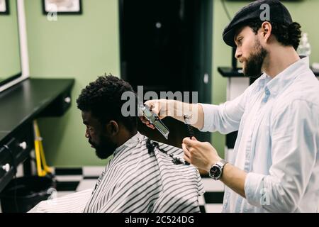 Portrait of young black man in barbershop.Handsome African guy makes new haircut in barber shop salon. Stock Photo