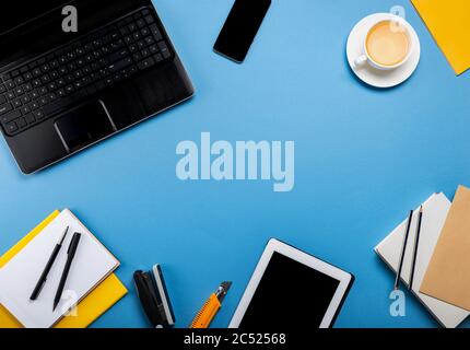 Online work or education concept. Laptop, tablet computer, smartphone, notepad, book, stationery on the blue background. Top view with copy space. Stock Photo