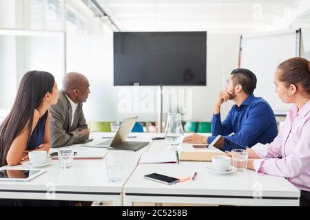 Multicultural business team in a meeting with video conference on monitor while brainstorming Stock Photo