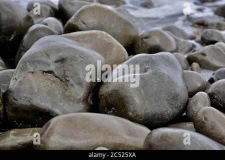 Natural backgrounds and textures of pebbles, stones and rocks on the beach in South Wales. Close up of the different sizes patterns. Stock Photo