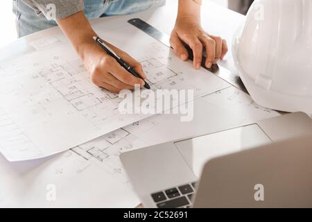 Top view of Engineer or architect holding pen with drawings in construction on blueprints in office. Engineering and construction concept. Stock Photo