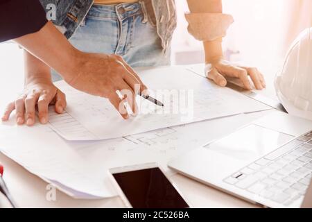 Engineer or architect working and discussing with blueprint and holding pencil on hand in office. concept of teamwork and partnership. Stock Photo