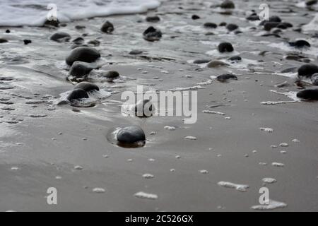 Natural backgrounds and textures of pebbles, stones and rocks on the beach in South Wales. Close up of the different sizes patterns. Stock Photo