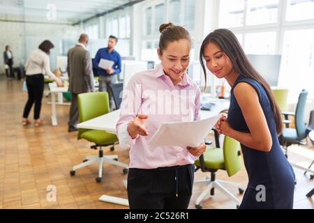 Two young business women discuss a document or project in the start-up office Stock Photo