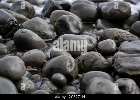 Natural backgrounds and textures of pebbles, stones and rocks on the beach in South Wales. Close up of the different sizes patterns. Stock Photo