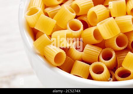 Heap of raw ditalini pasta in a white bowl. Macro close up view. Stock Photo