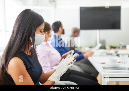 Business woman wearing face mask because of Covid-19 using smartphone in a video conference meeting Stock Photo
