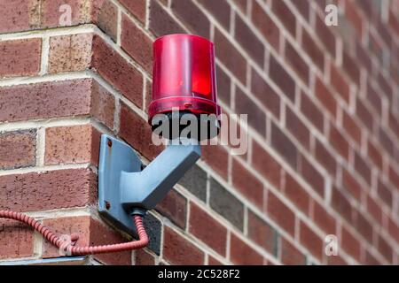 Red warning light on brick building outside of parking entrance. Stock Photo