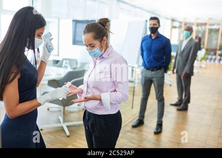 Business people disinfecting hands and measuring fever in front of the office as protection because of Covid-19 Stock Photo
