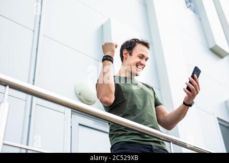 Surprised man holding phone looking at phone shocked by unexpected social media news. Astonished young man amazed stunned by mobile online content out Stock Photo
