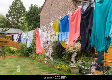Washing hanging on long line drying in the gusty windy weather. Full length of my garden taken up with washing drying and blowing around end to end. Stock Photo