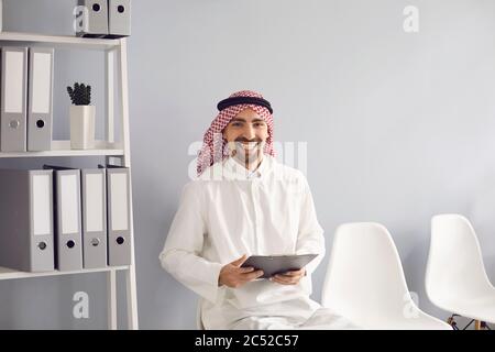 Arab man with black bag smiling in office. Stock Photo