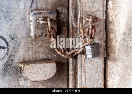 Close up macro photo of metal padlock and orange tinted rusty old chains at a locked door. Stock Photo