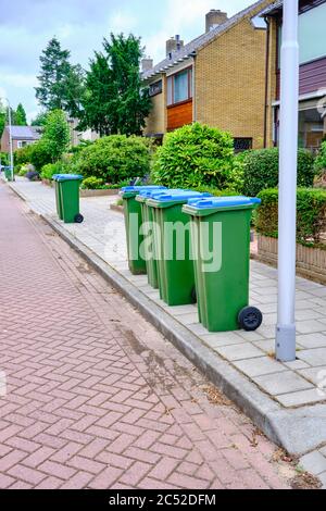 A group of Garbage cans on the side of the road waiting to be emptied. GReen blue waste bin in street, the Netherlands Stock Photo