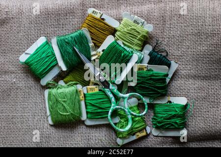 Various threads of different shades of green and small scissors Stock Photo