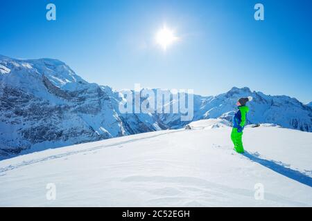 Boy in hiking class stepping on virgin snow on mountain summit winter activity concept full height portrait with panorama copy space Stock Photo