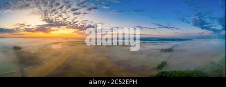 Sunrise glow over a foggy field in bavaria, germany at a wonderful morning in summer. Stock Photo