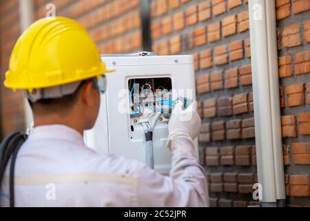 Air conditioning technician checking the power, Thailand Stock Photo