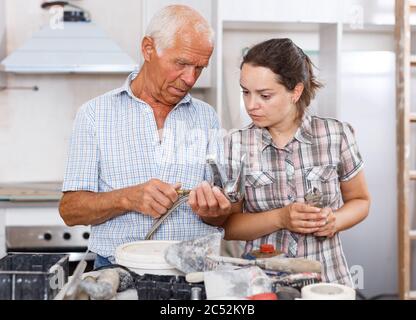 Young woman and her elderly father discussing installing faucet during repairs in their apartment Stock Photo