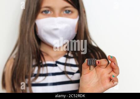Portrait of a girl wearing a face mask holding typographic characters spelling the word hope Stock Photo