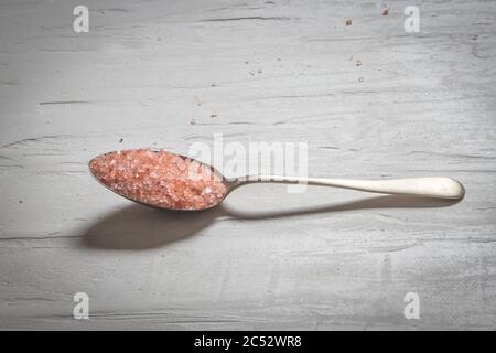 Antique silver spoons with various types of salts and spices laid out in patterns on a dark textured background Stock Photo