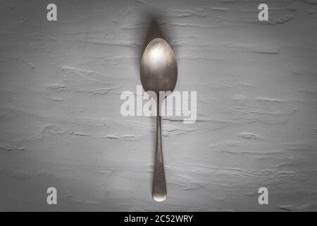 Antique silver spoon laid out on a dark textured background Stock Photo