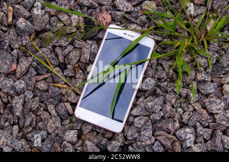 Smartphone with a broken screen. Broken phone on the stones. Stock Photo