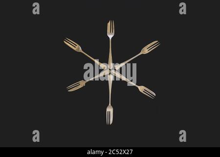 Antique silver forks laid out in patterns on a dark textured background Stock Photo