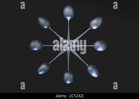 Antique silver spoons laid out in patterns on a dark textured back ground Stock Photo