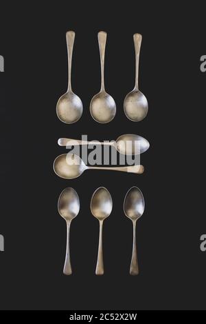 Antique silver spoons laid out in patterns on a dark textured back ground Stock Photo