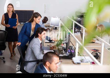 Focused coworkers of different nationalities engaged in business activities in busy open plan office Stock Photo