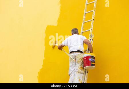 Man painting house wall yellow. Stock Photo