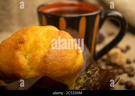 Fresh cupcake, coffee mug and coffee beans on a homespun fabric with a rough texture. Close up Stock Photo